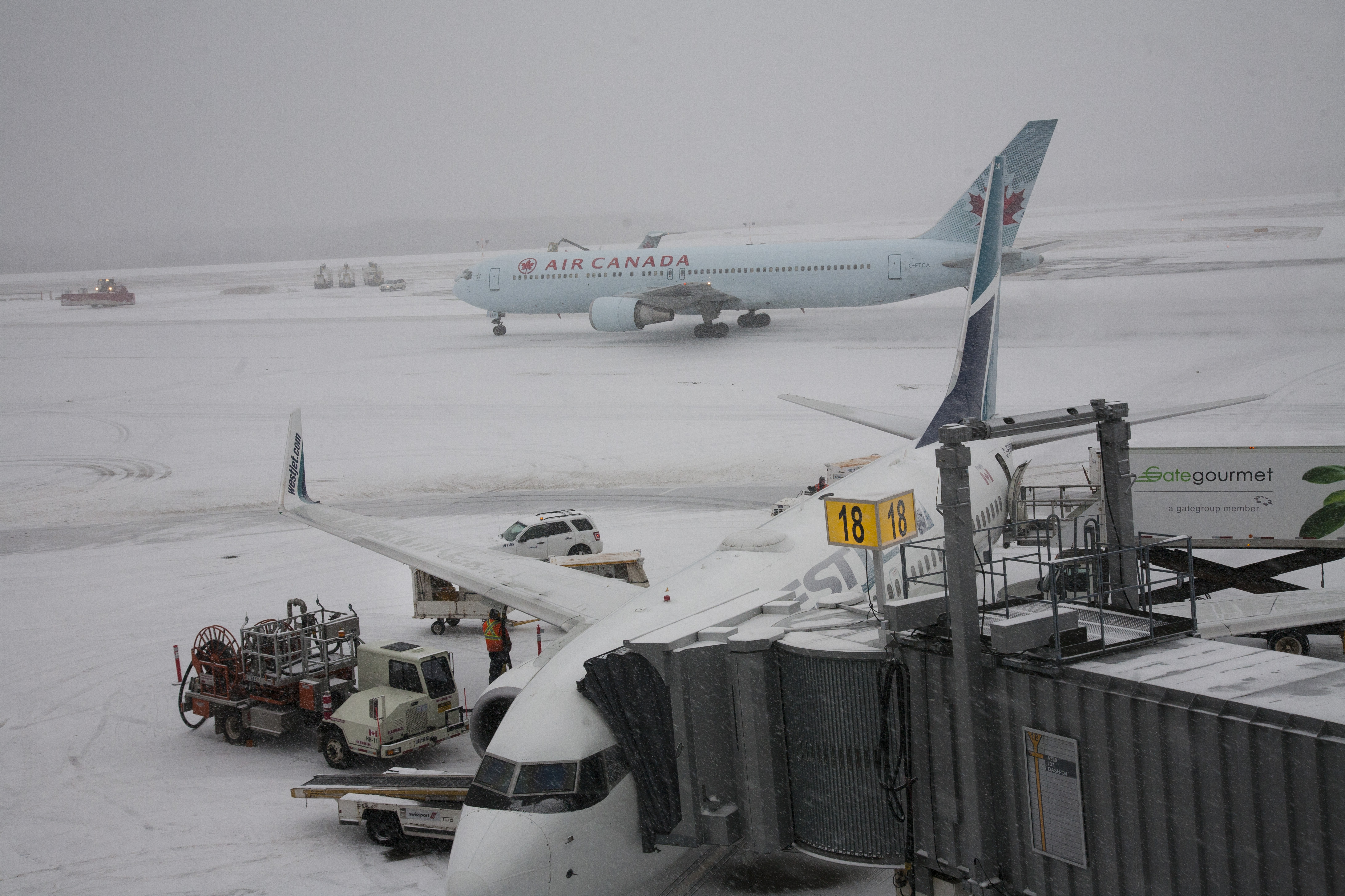 Crews at Halifax's Stanfield Airport ready a Westjet plane for it's next flight as an Air Canada plane makes it way to the gate on a snowy day. Friday January 6, 2017 (Mike Harvey)