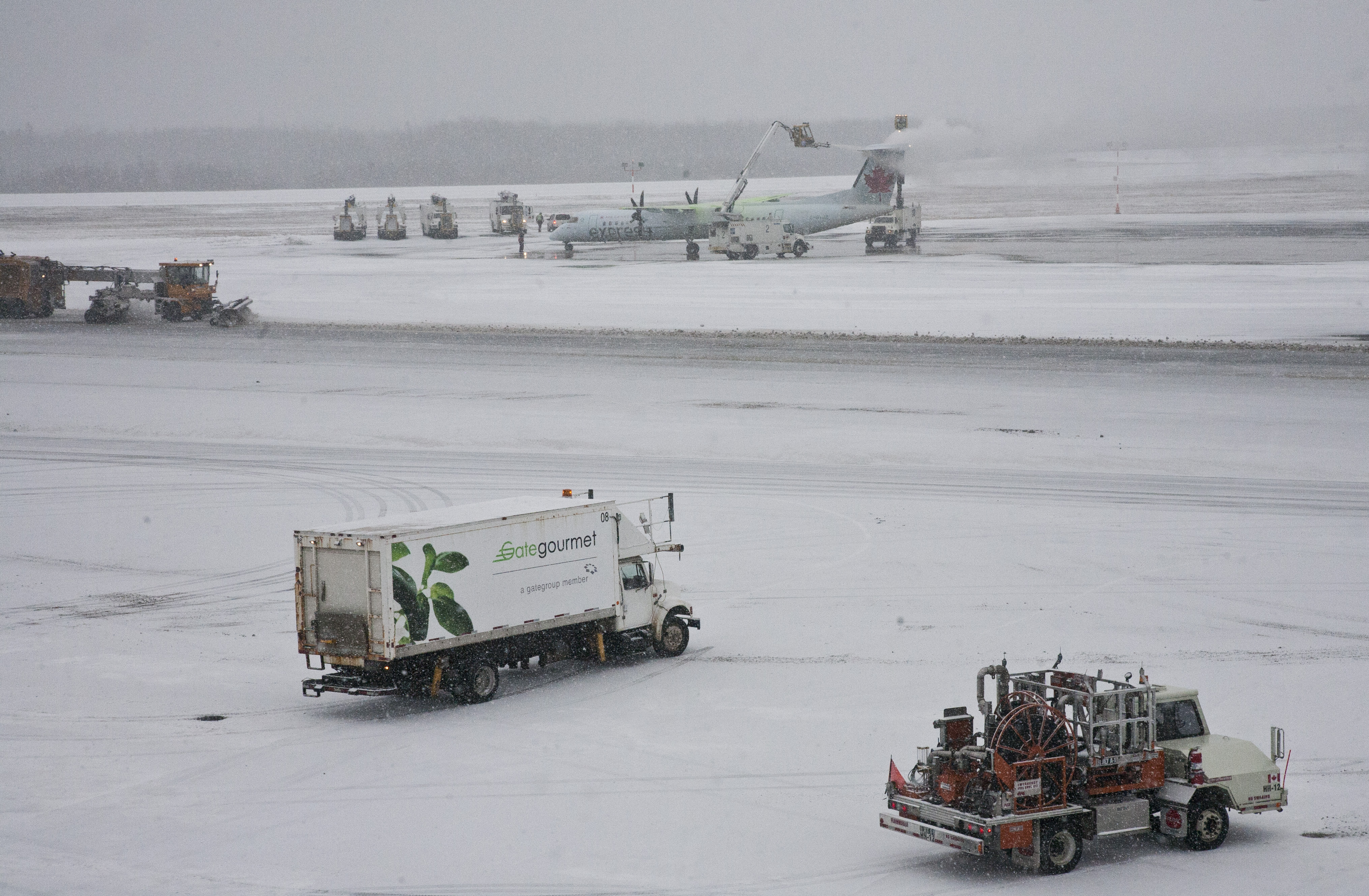 An Air Canada Express plane gets de-iced while other vehicles make thier way around the taramac at Halifax's Stanfield airport on a snowy Friday. Friday January 6, 2017. (Mike Harvey)