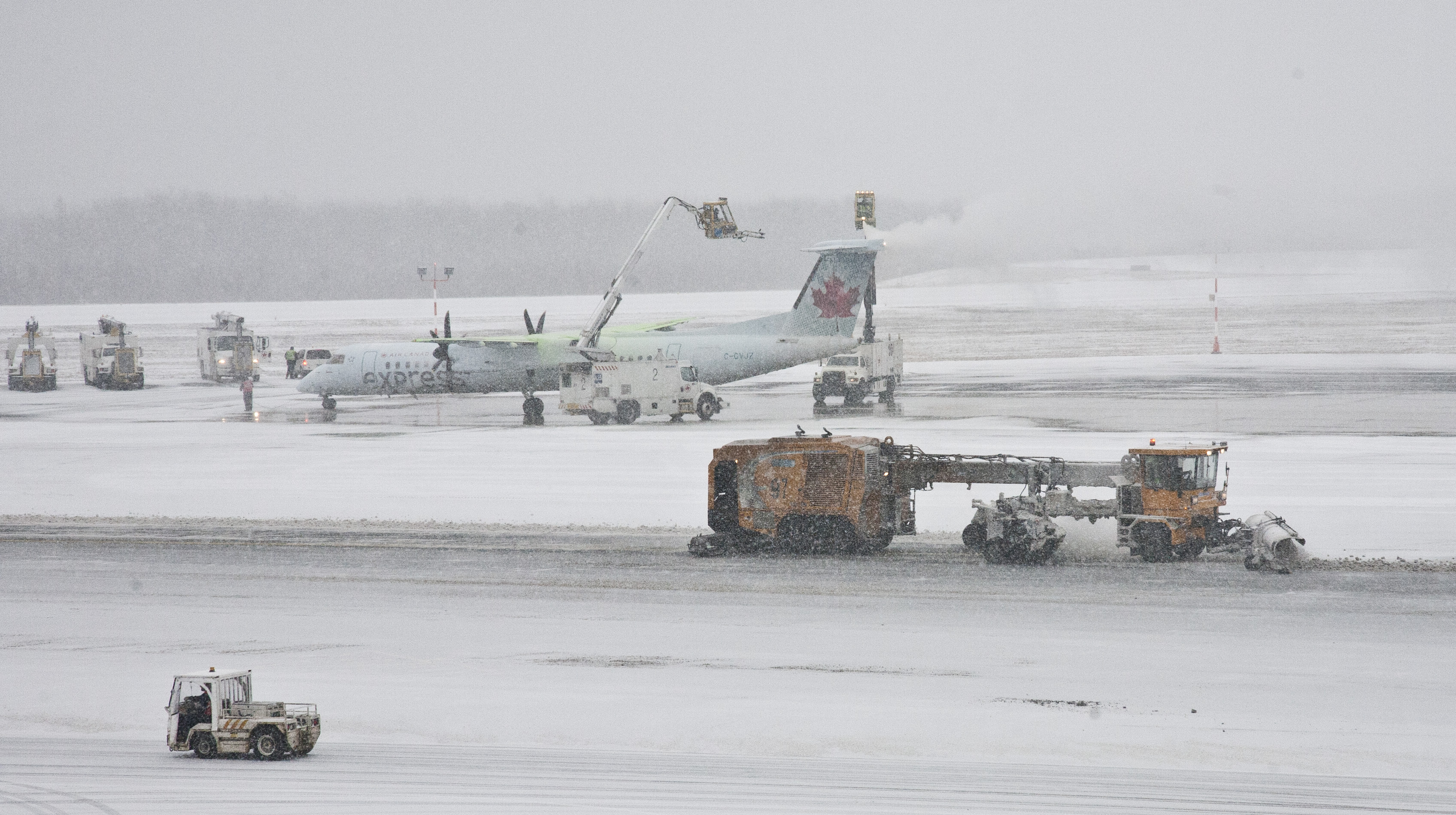 An Air Canada Express plane gets de-iced while a plow clears snow on the taramac at Halifax's Stanfield airport on a snowy Friday. Friday January 6, 2017. (Mike Harvey)